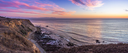Colorful coastal view of tall cliffs and ocean waves crashing into the shore below at sunset, Golden Cove, Rancho Palos Verdes, Californiaの写真素材