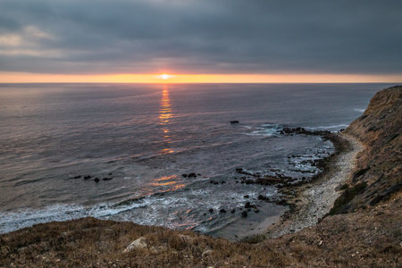 As the sun sets over Golden Cove, its tranquil waters reflect the warm hues of the sky, offering a serene escape amidst the rugged cliffs of Rancho Palos Verdes, California.の写真素材