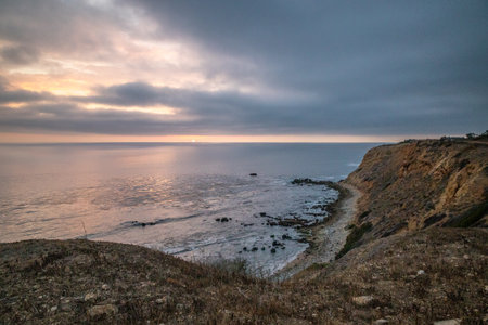 As the sun sets over Golden Cove, its tranquil waters reflect the warm hues of the sky, offering a serene escape amidst the rugged cliffs of Rancho Palos Verdes, California.の写真素材