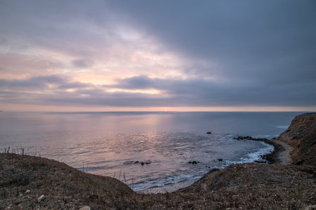 As the sun sets over Golden Cove, its tranquil waters reflect the warm hues of the sky, offering a serene escape amidst the rugged cliffs of Rancho Palos Verdes, California.の写真素材
