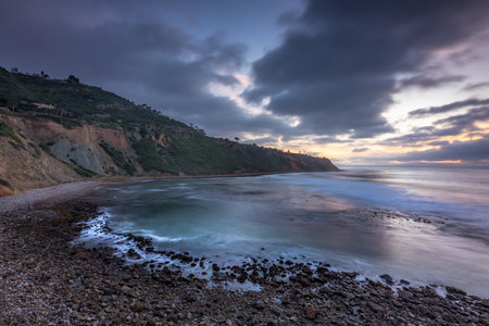 Embark on a serene journey along Bluff Trail, Palos Verdes, Estate, where the sun dips below Bluff Cove, illuminating rugged cliffs and serene ocean waves, creating a tranquil coastal landscape.の写真素材