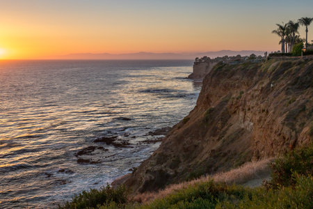 As the sun sets over Golden Cove, its tranquil waters reflect the warm hues of the sky, offering a serene escape amidst the rugged cliffs of Rancho Palos Verdes, California.の写真素材
