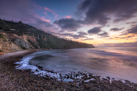 Embark on a serene journey along Bluff Trail, Palos Verdes Estates, where the sun dips below Bluff Cove, illuminating rugged cliffs and serene ocean waves, creating a tranquil coastal landscape.の写真素材