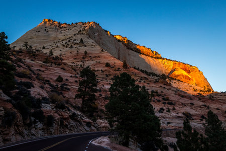 Winding roads lead through Zion National Park, where sandstone cliffs glow in the dusk light, providing a peaceful retreat for travelers.の写真素材
