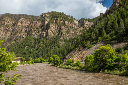 Colorado River winds through the scenic mountains of Glenwood Springs, Colorado, surrounded by lush greenery and rugged cliffs on a sunny day.の写真素材