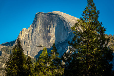 Half Dome rises prominently in Yosemite Valley, where a helicopter explores the serene wilderness of...