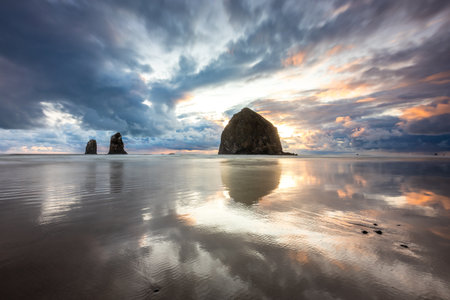 Breathtaking sunset at Cannon Beach with colorful sky and reflections from the calm water on the beachの写真素材