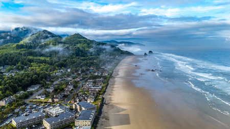 Aerial shot over Cannon Beach, Oregon on a foggy morning, featuring Haystack Rock and moody coastal sceneryの写真素材
