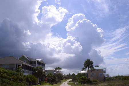 Florida beach houses with palm trees and huge dramatic cloud and blue sky.の写真素材