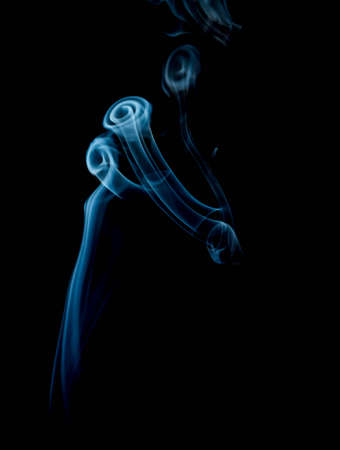 Incense smoke spiral colors on black backgroundの写真素材