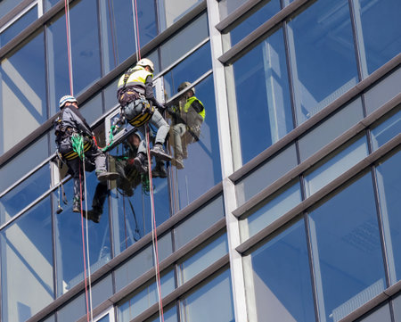 High-rise workers with climbing equipment work in the high building.