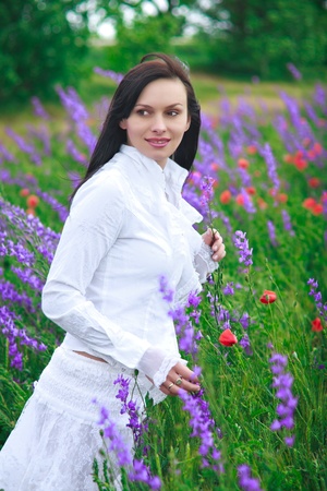 a beautiful young woman smiling, walking in a field of flowersの写真素材