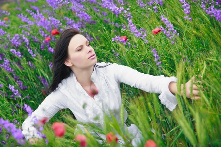 a beautiful young woman smiling, walking in a field of flowersの写真素材