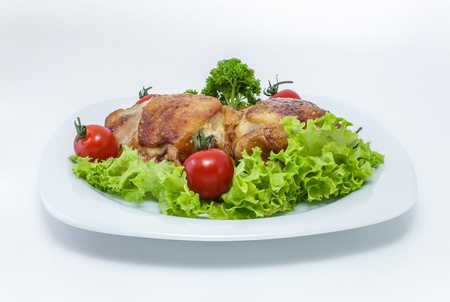 Fried chicken pieces on a plate with tomatoes, lettuce and parsley. Taken on a sheet of white plastic. Is not an isolate.の写真素材