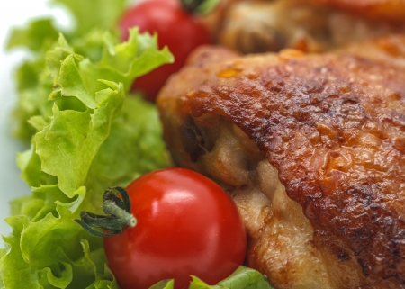 Fried chicken pieces on a plate with lettuce and tomatoes. Taken on a sheet of white plastic. Is not an isolate.の写真素材