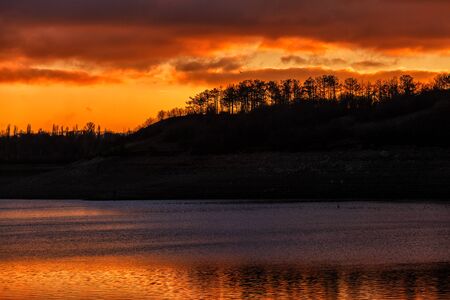 red sunset over the water. the rays of the setting sun reflected on the water surfaceの写真素材