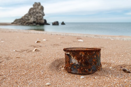 Rusty tin can on beach - concept of environment backgroundの写真素材