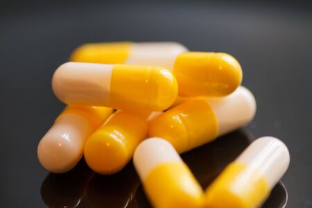 Yellow-white capsules on a dark background close-upの写真素材
