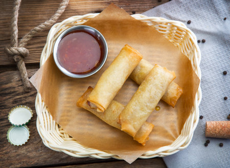 Stuffed pancakes with sauce in a wicker plate on an old table