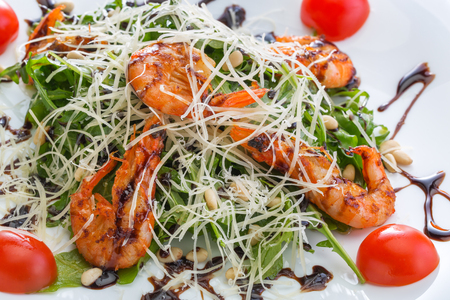 Salad with shrimps and cheese on a white plate with sliced tomatoes on the edgesの写真素材