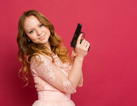 Girl posing with a gun on a colored backgroundの写真素材