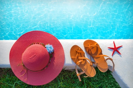 pool with clear turquoise water and a hat with shoes on the shoreの写真素材