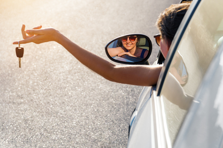 Happy girl in a car showing a key and smileの写真素材