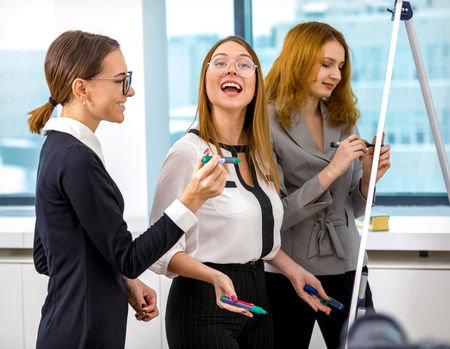 girl with coworkers draw charts and diagrams on whiteboard markersの写真素材