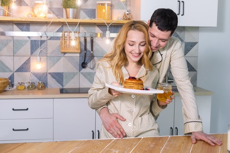 young couple in pajamas in the kitchen in the morning. Breakfast. Morning of a young familyの写真素材