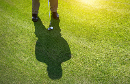 man playing Golf on green grass in sunlight. Free space for text.の写真素材