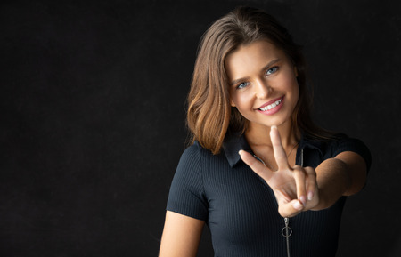 beautiful young model smiling and showing a gesture. Studio, dark background, energetic and beautiful modelの写真素材