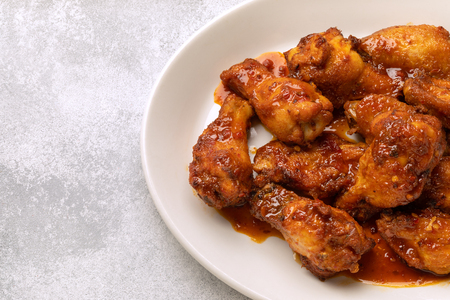 chicken legs with hot sauce on a white plate. restaurant menu. place for text and copypastの写真素材