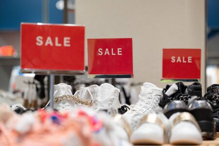goods in stores and a red sign on sales discounts. mocap for text and concept of sales and trade in light industry. signs advertising the sale of shoes at a reduced priceの写真素材