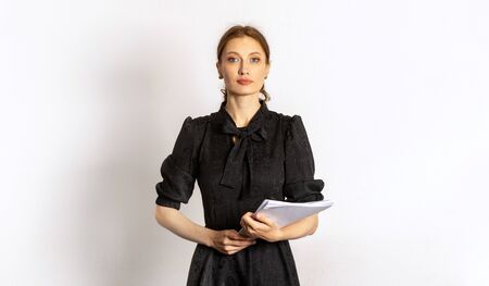 girl secretary in a dark dress with documents in hand against a light wall.の写真素材
