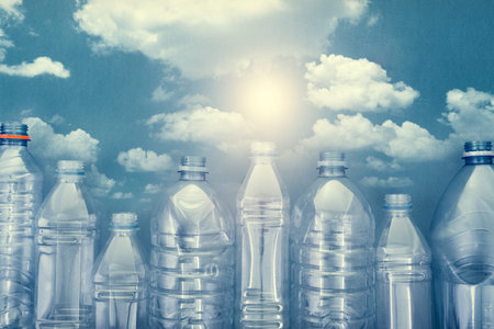 plastic bottles on blue cardboard with a picture of a blue sky with white clouds and a bright sun. the concept of the city of bottlesの写真素材