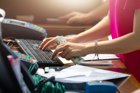 The woman is holding a hundred dollars and typing something on the keyboard