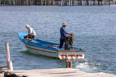 Vietnam Phu Quoc island 2 April 2019 Vietnamese fisherman starts the motor on the boat and his partner puts things in order on the boatのeditorial素材