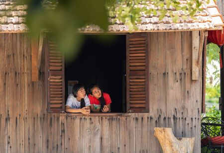 Vietnam Phu Quoc island 2 April 2019. two waitress girls look cautiously out the open window of the cafe from the burning in the airのeditorial素材