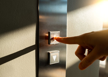 a womans finger presses the Elevator button in the sunlight