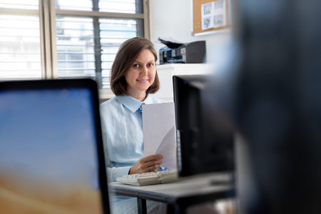 Young woman working in the office with documents near the computer