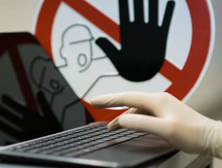 Male hand with glove at Notebook. Concept of stopping internet crime.の写真素材