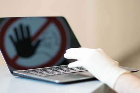 Male hand with glove at Notebook. Concept of stopping internet crime.の写真素材