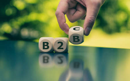 Business to Business or Busness to Consumer? Hand turns a dice and changes the expression "B2B" to "B2C" (or vice versa)の写真素材