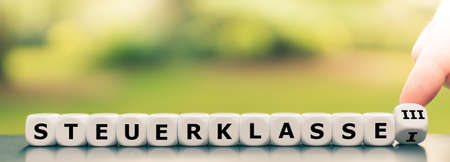 Hand turns a dice and changes the German expression "Steuerklasse I" ("German tax class 1") to ("Steuerklasse III" ("German tax class 3"),の写真素材