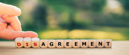 Hand turns dice and changes the expression "disagreement" to "agreement".の写真素材
