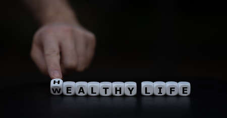 Hand turns dice and changes the expression "wealthy life" to "healthy life".の写真素材