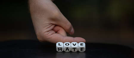 Hand turns dice and changes the word "hate" to "love".の写真素材