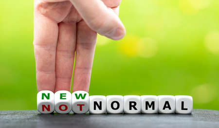 Hand turns dice and changes the expression "not normal" to "new normal".の写真素材
