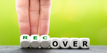 Hand turns dice and changes the word over to recover.の写真素材