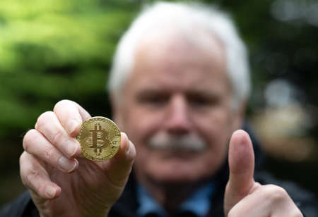 Symbol for Bitcoin as a Retirement Plan Investment. Old man holding a Bitcoin.の写真素材